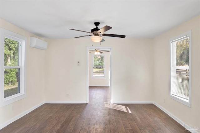 empty room featuring a wall mounted air conditioner, dark wood finished floors, and baseboards