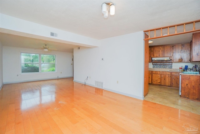 unfurnished living room with ceiling fan, sink, and light hardwood / wood-style floors