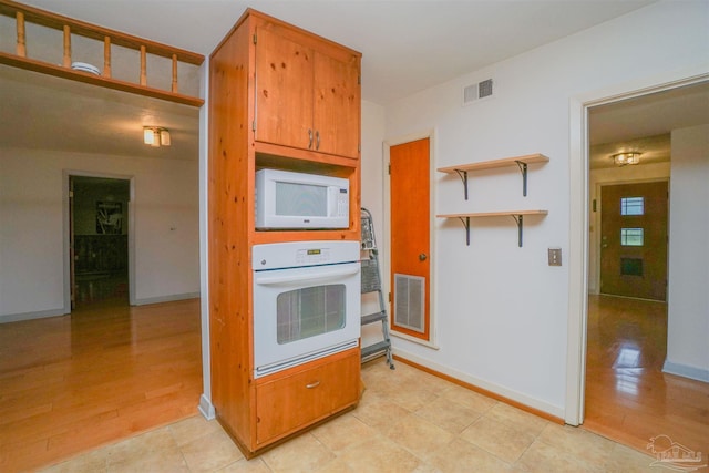 kitchen with white appliances and light hardwood / wood-style floors