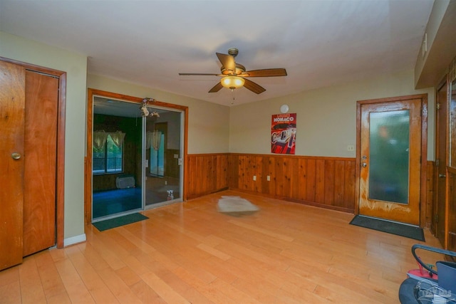 unfurnished room featuring ceiling fan, wood walls, and light wood-type flooring