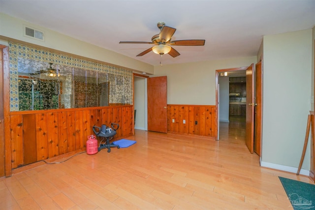 spare room with wooden walls, light hardwood / wood-style flooring, and ceiling fan