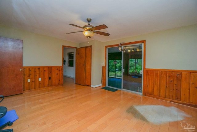 spare room with ceiling fan, light hardwood / wood-style floors, and wood walls