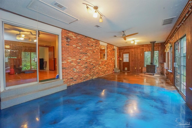 unfurnished living room featuring a wood stove, plenty of natural light, and concrete flooring