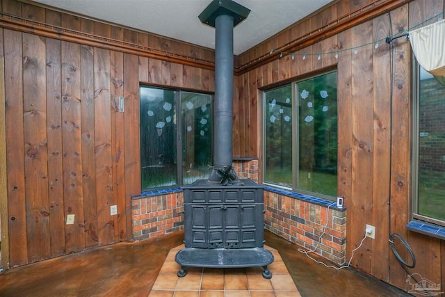 interior details featuring a wood stove, wood walls, concrete flooring, and a textured ceiling