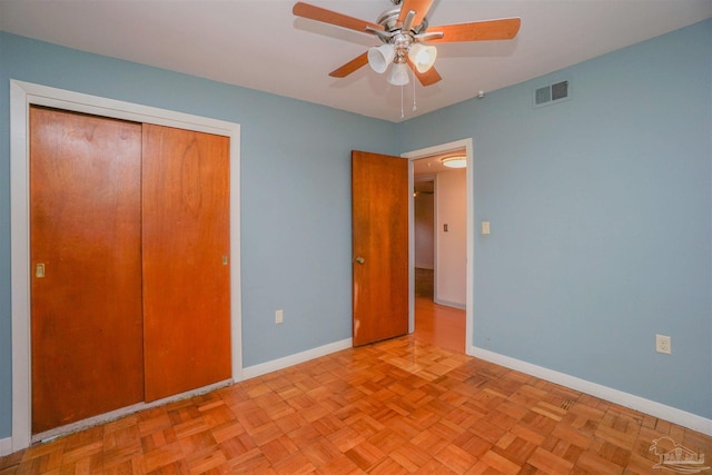 unfurnished bedroom with ceiling fan, a closet, and light parquet floors