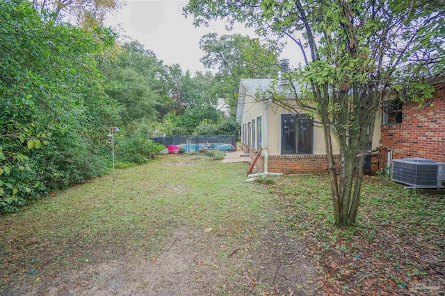 view of yard featuring a pool and central air condition unit