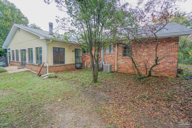 back of house with central air condition unit and a yard