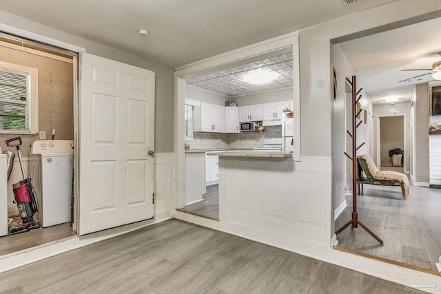 kitchen featuring ceiling fan, white appliances, white cabinetry, washer / dryer, and hardwood / wood-style floors