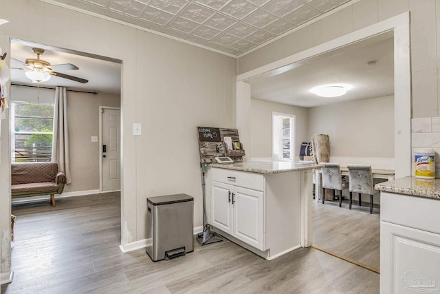 kitchen featuring light stone countertops, ceiling fan, white cabinets, and light hardwood / wood-style flooring