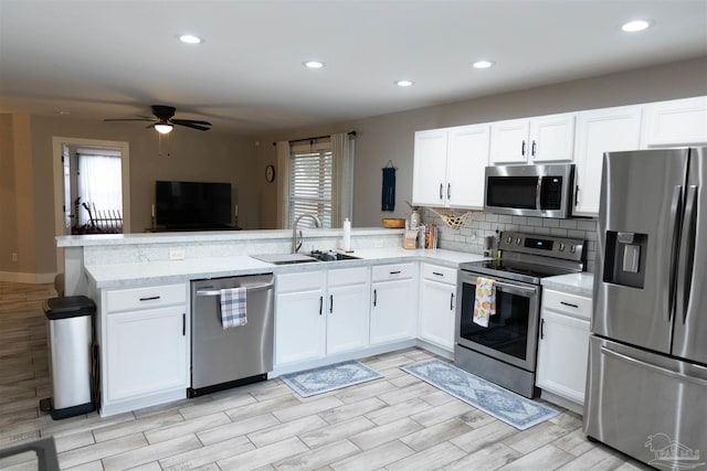 kitchen featuring sink, white cabinetry, kitchen peninsula, a healthy amount of sunlight, and appliances with stainless steel finishes