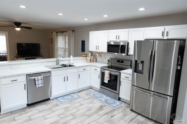 kitchen featuring stainless steel appliances, ceiling fan, white cabinets, and sink