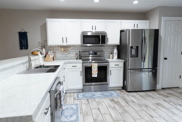 kitchen featuring stainless steel appliances, white cabinets, decorative backsplash, and sink