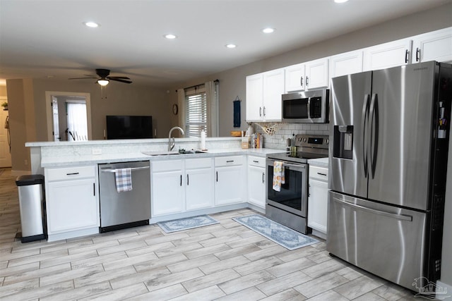 kitchen with appliances with stainless steel finishes, ceiling fan, white cabinets, and sink