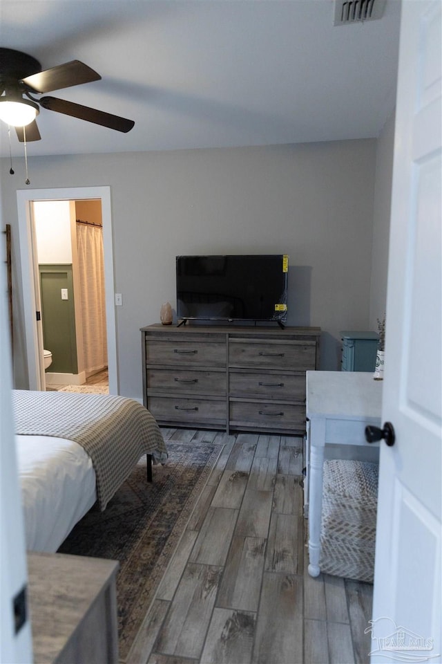 bedroom with ensuite bathroom, ceiling fan, and dark wood-type flooring