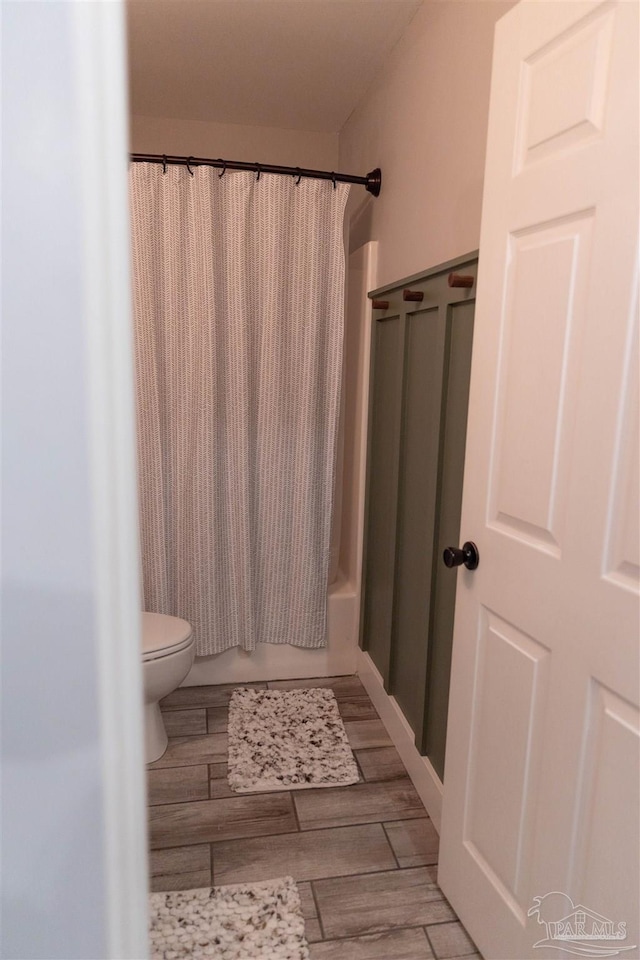 bathroom featuring shower / bathtub combination with curtain and toilet