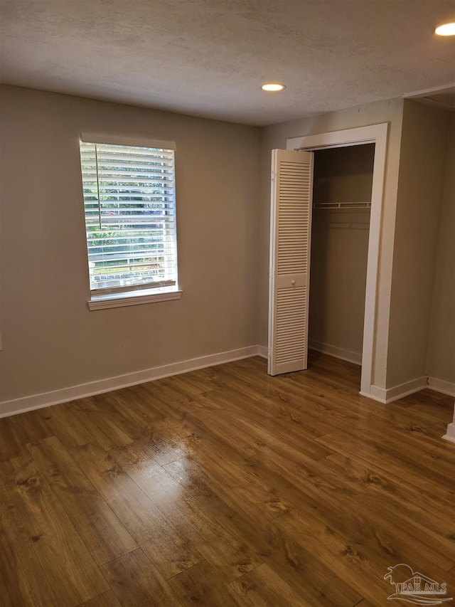 unfurnished bedroom featuring dark hardwood / wood-style flooring, a closet, and a textured ceiling