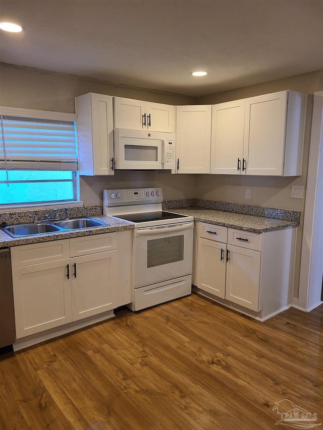 kitchen with hardwood / wood-style flooring, sink, white cabinets, and white appliances