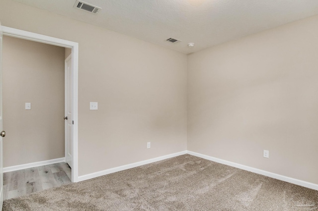 carpeted empty room featuring a textured ceiling