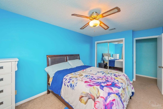 bedroom featuring a ceiling fan, a textured ceiling, a closet, carpet floors, and visible vents