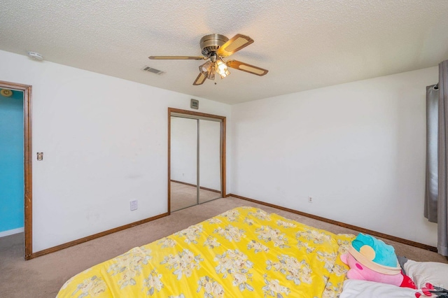 carpeted bedroom with baseboards, a ceiling fan, a textured ceiling, and a closet