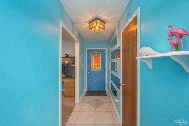 interior space featuring baseboards, a textured ceiling, and light tile patterned floors
