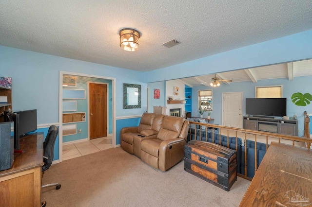 carpeted living room featuring tile patterned floors, visible vents, a ceiling fan, beamed ceiling, and a large fireplace