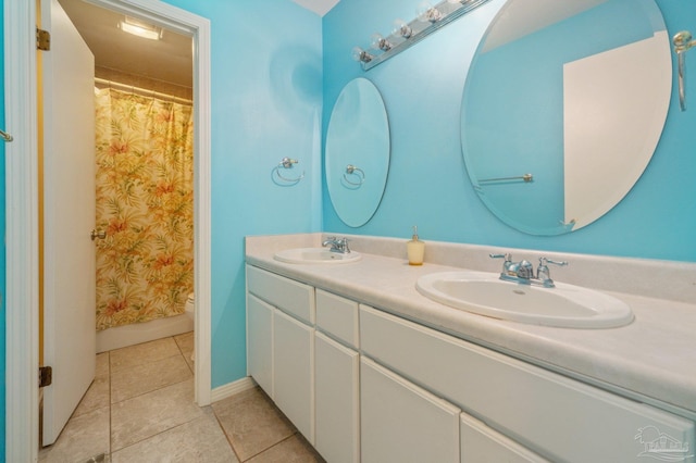 full bathroom with double vanity, tile patterned flooring, toilet, and a sink