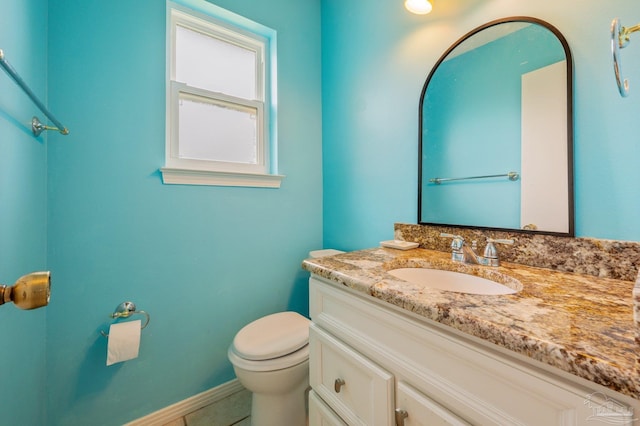 half bathroom featuring tile patterned flooring, baseboards, toilet, and vanity