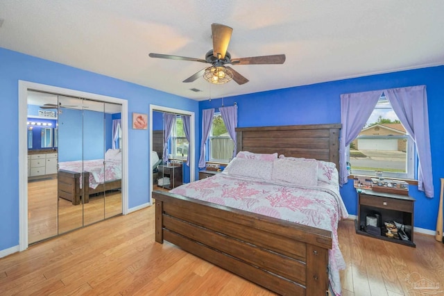 bedroom with two closets, visible vents, wood finished floors, and multiple windows