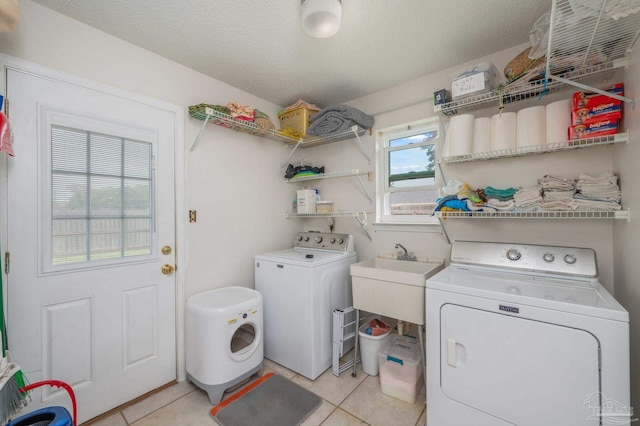 washroom featuring washing machine and dryer, a sink, light tile patterned flooring, and laundry area