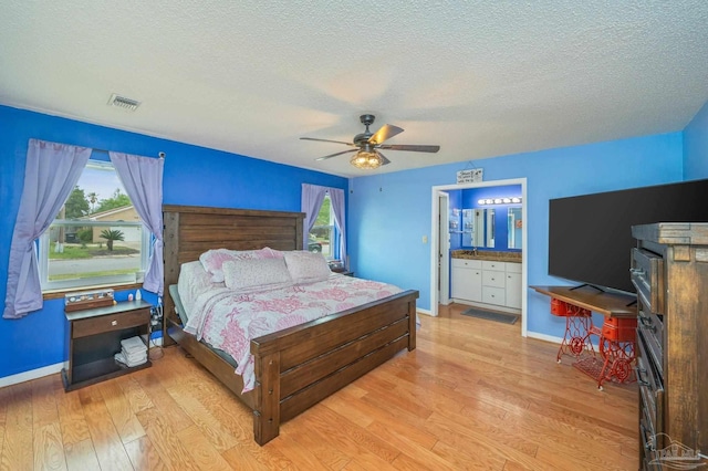 bedroom featuring a textured ceiling, light wood-type flooring, ceiling fan, baseboards, and visible vents