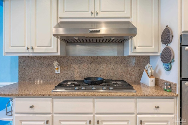 kitchen with stainless steel gas cooktop, decorative backsplash, range hood, and white cabinetry