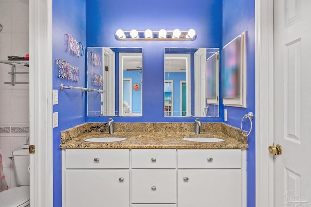 bathroom featuring double vanity, toilet, and a sink