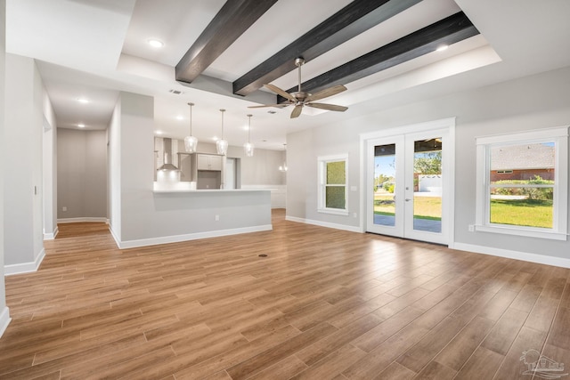 unfurnished living room featuring light wood finished floors, beam ceiling, french doors, and baseboards