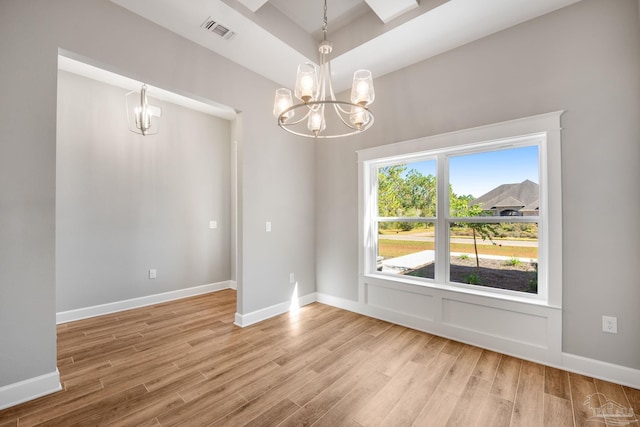 unfurnished room with visible vents, baseboards, light wood-type flooring, and an inviting chandelier