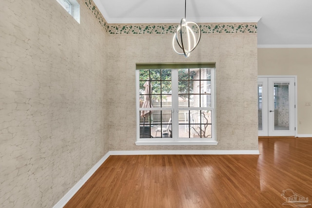 unfurnished dining area featuring french doors, ornamental molding, wood finished floors, and baseboards