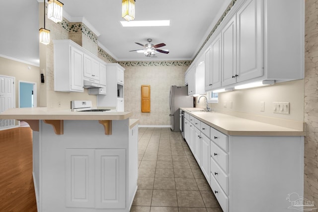 kitchen with ornamental molding, a skylight, range, and a breakfast bar area