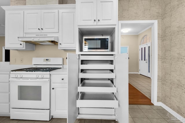 kitchen with stainless steel microwave, gas range gas stove, white cabinetry, and under cabinet range hood