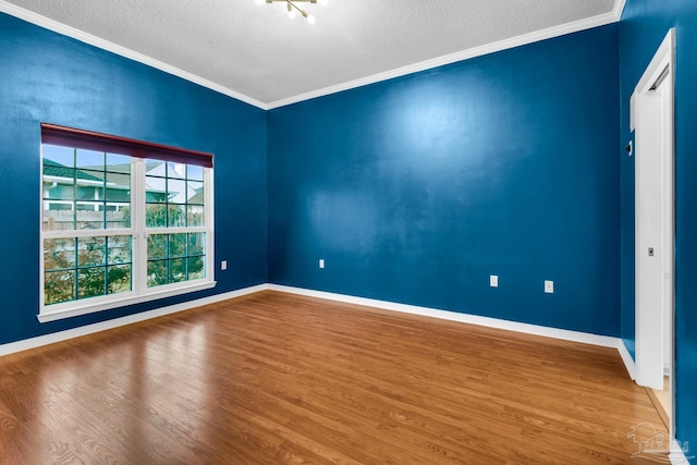 unfurnished room featuring baseboards, a textured ceiling, ornamental molding, and wood finished floors