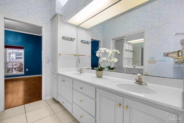 bathroom featuring tile patterned flooring, a sink, and wallpapered walls