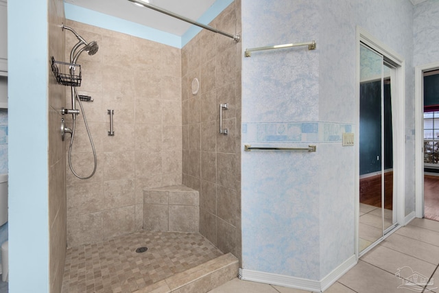 bathroom featuring tile patterned flooring, baseboards, and tiled shower