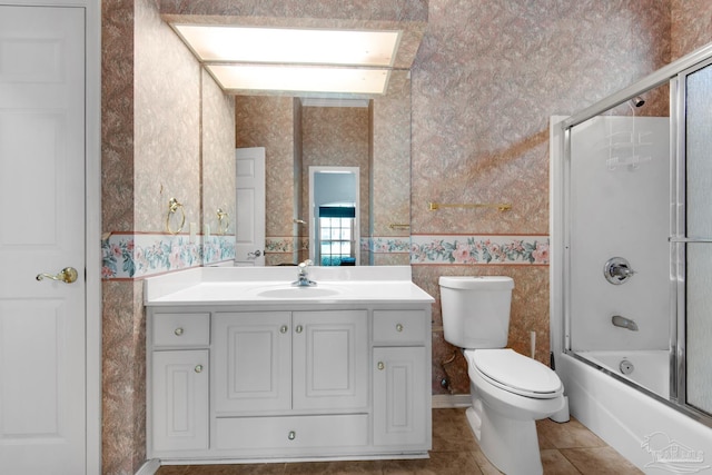 full bath featuring wallpapered walls, bath / shower combo with glass door, toilet, tile patterned floors, and vanity