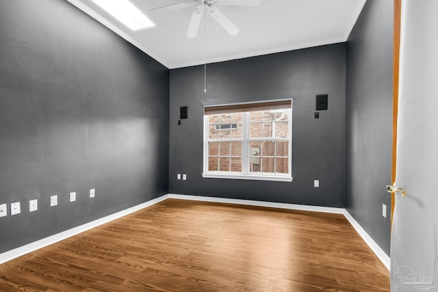 empty room with ceiling fan, crown molding, baseboards, and wood finished floors