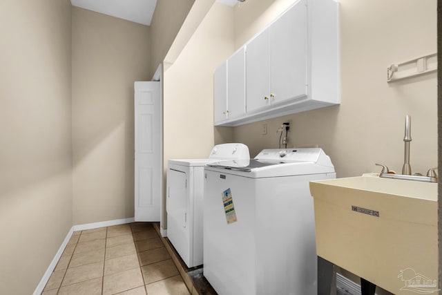 laundry area featuring washer and clothes dryer, light tile patterned floors, cabinet space, a sink, and baseboards