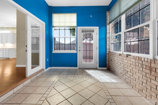 entryway featuring brick wall, tile patterned flooring, and baseboards