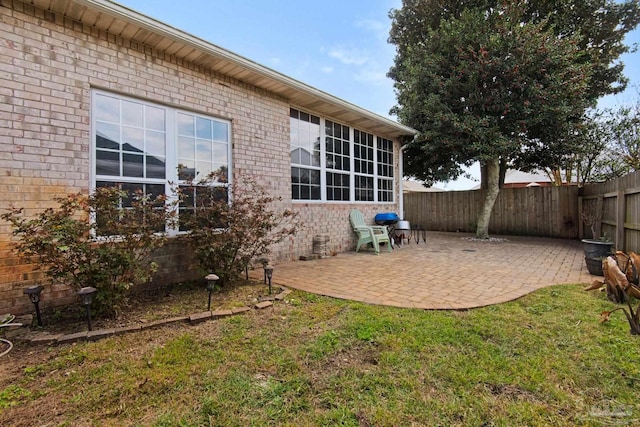 rear view of house with brick siding, a patio, and fence