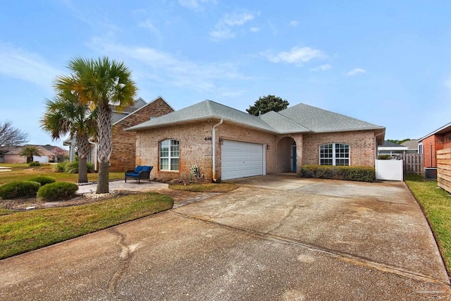 single story home featuring a garage, concrete driveway, brick siding, and fence