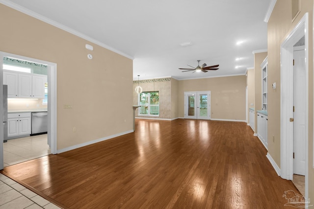 unfurnished living room featuring baseboards, french doors, light wood-type flooring, and crown molding