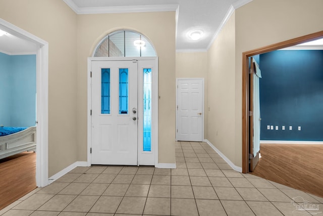 entrance foyer with light tile patterned floors, baseboards, and crown molding