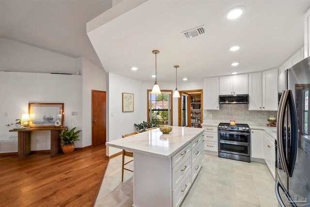 kitchen featuring white cabinets, pendant lighting, appliances with stainless steel finishes, a center island, and light hardwood / wood-style floors